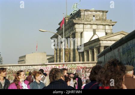 Berliner und Besucher aus aller Welt kommen, um ihre kürzlich gefundene Freiheit zu genießen und ein kleines Stück der Mauer zu nehmen. Stockfoto