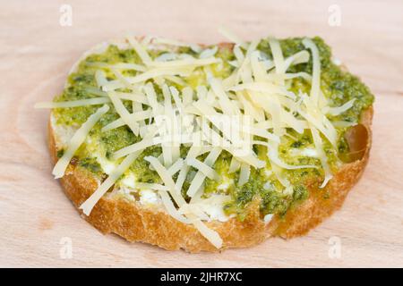 Kleines offenes Sandwich mit vegetarischem Aufstrich und geriebenem Käse auf Holzbrett, selektiver Fokus Stockfoto