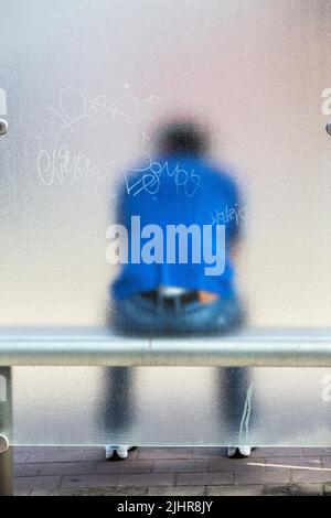 Silhouette einer Person, die in einer Bushütte sitzt, durch ein Milchglasfenster gesehen. Stockfoto