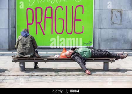 Zwei Männer auf einer öffentlichen Bank, einer saß, der andere schlief, auf dem Rücken liegend. Stockfoto