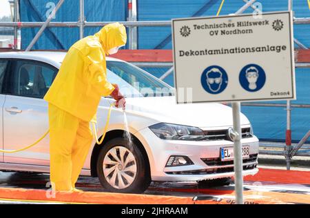 Nordhorn, Deutschland. 20.. Juli 2022. Mitarbeiter des Technischen Hilfswerks (THW) reinigen und desinfizieren ein Fahrzeug in einer Dekontaminationsanlage, die auf einem Bauernhof in einer Überwachungszone unterwegs war. Nach dem Ausbruch der Afrikanischen Schweinepest in einem Betrieb im südlichen Emsland ergreifen die betroffenen Landkreise weitere Maßnahmen zur Bekämpfung der Tierseuche. In den Grafschaften Bentheim und Emsland in Nordhorn wurde ein gemeinsames Tierseuchenlogistikzentrum in Betrieb genommen. Quelle: Friso Gentsch/dpa/Alamy Live News Stockfoto