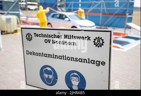 Nordhorn, Deutschland. 20.. Juli 2022. Mitarbeiter des Technischen Hilfswerks (THW) reinigen und desinfizieren ein Fahrzeug in einer Dekontaminationsanlage, die auf einem Bauernhof in einer Überwachungszone unterwegs war. Nach dem Ausbruch der Afrikanischen Schweinepest in einem Betrieb im südlichen Emsland ergreifen die betroffenen Landkreise weitere Maßnahmen zur Bekämpfung der Tierseuche. In den Grafschaften Bentheim und Emsland in Nordhorn wurde ein gemeinsames Tierseuchenlogistikzentrum in Betrieb genommen. Quelle: Friso Gentsch/dpa/Alamy Live News Stockfoto