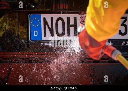 Nordhorn, Deutschland. 20.. Juli 2022. Mitarbeiter des Technischen Hilfswerks (THW) reinigen und desinfizieren ein Fahrzeug, das auf einem Bauernhof in einer Überwachungszone unterwegs war. Nach dem Ausbruch der Afrikanischen Schweinepest in einem Betrieb im südlichen Emsland ergreifen die betroffenen Landkreise weitere Maßnahmen zur Bekämpfung der Tierseuche. In den Grafschaften Bentheim und Emsland in Nordhorn wurde ein gemeinsames Tierseuchenlogistikzentrum in Betrieb genommen. Quelle: Friso Gentsch/dpa/Alamy Live News Stockfoto