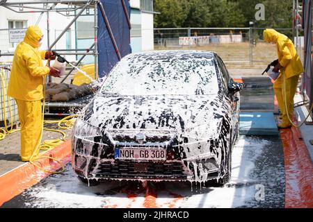 Nordhorn, Deutschland. 20.. Juli 2022. Mitarbeiter des Technischen Hilfswerks (THW) reinigen und desinfizieren ein Fahrzeug, das auf einem Bauernhof in einer Überwachungszone unterwegs war. Nach dem Ausbruch der Afrikanischen Schweinepest in einem Betrieb im südlichen Emsland ergreifen die betroffenen Landkreise weitere Maßnahmen zur Bekämpfung der Tierseuche. In den Grafschaften Bentheim und Emsland in Nordhorn wurde ein gemeinsames Tierseuchenlogistikzentrum in Betrieb genommen. Quelle: Friso Gentsch/dpa/Alamy Live News Stockfoto