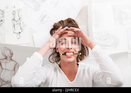 Lächelnder Künstler, der auf dem Boden lag, war ein Bleistift von oben Stockfoto