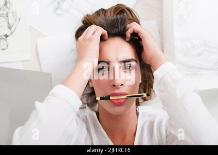 Schockierte Frau schaut mit Bleistift im Mund auf die Kamera Stockfoto