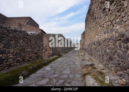 Alte Kopfsteinpflasterstraße in Pompeji, mit dem Vesuv im Hintergrund Stockfoto