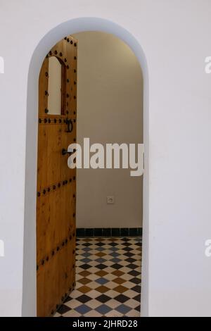 Die alte Holztür öffnet sich zu einem kleinen weißen zimmer im arabischen Stil Stockfoto