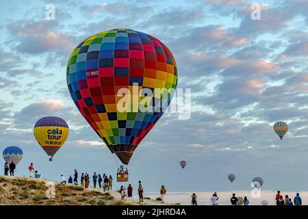 GOREME/TÜRKEI - 30. Juni 2022: Heißluftballon fliegt tief über die Stadt goreme in der Nähe der Menschen Stockfoto