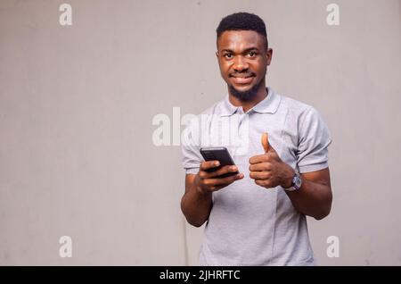 Nahaufnahme eines niedlichen Mannes, der sein Telefon benutzt und lächelt Stockfoto