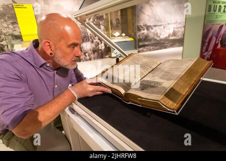 Birmingham, Großbritannien. 20.. Juli 2022. Tom Epps, Cultural Partnership Manager der Library of Birmingham, nimmt eine abschließende Anpassung an das seltene Shakespeare First Folio aus dem Jahr 1623 vor, bevor es zusammen mit vielen anderen bisher unsichtbaren Shakespeare-Artikeln und Büchern in der Library of Birmingham gezeigt wird. Die Ausstellung „alles für alle: Euer Shakespeare, eure Kultur“ läuft vom 22.. Juli bis zum 2022. November. Kredit: Peter Lopeman/Alamy Live Nachrichten Stockfoto