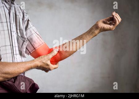 Schmerzen im Ellenbogengelenk des südostasiatischen älteren Mannes. Konzept von Ellenbogenschmerzen oder Arthrose. Stockfoto