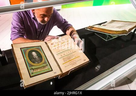 Birmingham, Großbritannien. 20.. Juli 2022. Tom Epps, Cultural Partnership Manager der Library of Birmingham, nimmt eine abschließende Anpassung an das seltene Shakespeare First Folio aus dem Jahr 1623 vor, bevor es zusammen mit vielen anderen bisher unsichtbaren Shakespeare-Artikeln und Büchern in der Library of Birmingham gezeigt wird. Die Ausstellung „alles für alle: Euer Shakespeare, eure Kultur“ läuft vom 22.. Juli bis zum 2022. November. Kredit: Peter Lopeman/Alamy Live Nachrichten Stockfoto