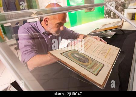 Birmingham, Großbritannien. 20.. Juli 2022. Tom Epps, Cultural Partnership Manager der Library of Birmingham, nimmt eine abschließende Anpassung an das seltene Shakespeare First Folio aus dem Jahr 1623 vor, bevor es zusammen mit vielen anderen bisher unsichtbaren Shakespeare-Artikeln und Büchern in der Library of Birmingham gezeigt wird. Die Ausstellung „alles für alle: Euer Shakespeare, eure Kultur“ läuft vom 22.. Juli bis zum 2022. November. Kredit: Peter Lopeman/Alamy Live Nachrichten Stockfoto