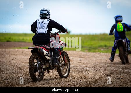 Ein Profi mit vollem Gang, der 2020 beim Rock Fest ein Motorrad auf einem schlammigen Feld fährt Stockfoto