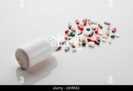 Eine Pille kann dein Leben verändern: Eine Pillenflasche liegt auf der Seite und in einem leeren Studio wird Medizin ausgegossen. Stockfoto