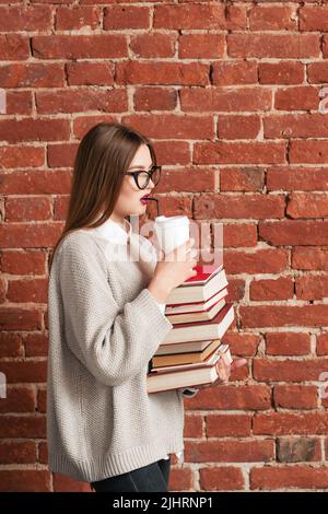 Profil des Studenten, der mit Büchern und Kaffee geht Stockfoto