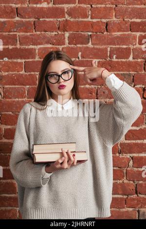 Müde Student mit Büchern zeigt schießen Geste Stockfoto