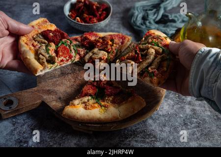 Diverse Kollegen oder Freunde nehmen Scheiben veganer Pizza und genießen das Abendessen. Stockfoto