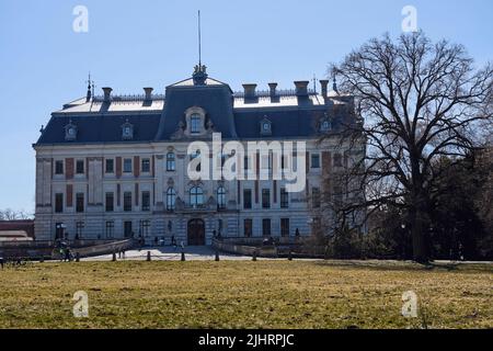 Neobarocke Burg und Grasfeld im Park der europäischen Stadt Pszczyna in Polen, klarer blauer Himmel in 2022 warmen sonnigen Frühlingstag am März. Stockfoto