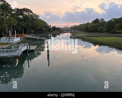 Der farbenfrohe Sonnenuntergang spiegelt sich im Fripp Island Channel mit Docks und Konstruktionen wider Stockfoto