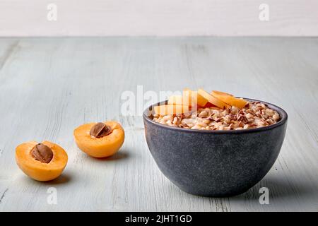 Gesundes Energie-Frühstück. Vollkorn-Haferflocken mit Leinsamen und Aprikosenstücken auf einem bemalten blauen Holztisch Stockfoto