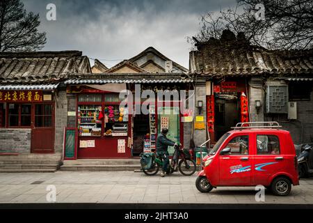 Ein rotes Elektroauto in der traditionellen Pekinger Straße in der chinesischen Straßenszene Stockfoto