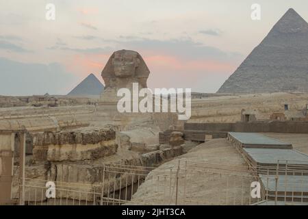 Landschaft mit ägyptischen Pyramiden, großer Sphinx und Silhouetten Antike Symbole und Wahrzeichen Ägyptens für Ihre Reise concep in goldenem Sonnenlicht. Der Stockfoto