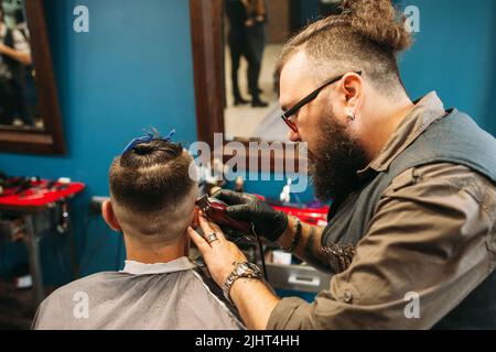 Stylist, der den männlichen Kopf im Friseurladen rasieren kann Stockfoto