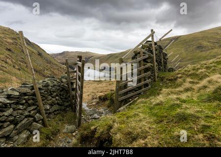 Ein Brückenweg durch ein Tor über dem Haweswater Reservoir bei Mardale Head im Lake District National Park, Cumbria, England. Stockfoto