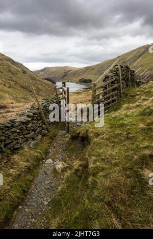 Ein Brückenweg durch ein Tor über dem Haweswater Reservoir bei Mardale Head im Lake District National Park, Cumbria, England. Stockfoto