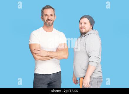 Zwei Arten von Männern. Fat Mann und fit reifen Mann posiert im Studio isoliert auf blauem Hintergrund. Zeit, um einen fitden Trainer neben dem Trainee zu stehen. Sportkonzept und Mensch Gesundheit. Stockfoto