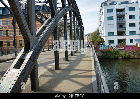 Eine Brücke mit Metallgeländern über dem Fluss und Graffiti im Hintergrund in Leipzig, Deutschland Stockfoto