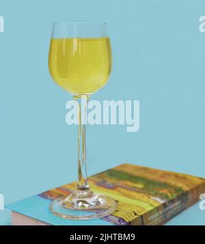 Limoncello im Glas, süßer italienischer Zitronenlikör, traditionelles starkes alkoholisches Getränk und Zitronen auf blauem Hintergrund. Stockfoto