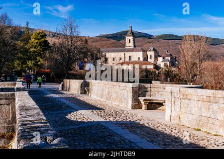 Die Puente del Perdón - Brücke der Begnadigung, ist eine steinerne Brücke über den Fluss Lozoya. Im Hintergrund das Monasterio de Santa María de El Paular - Stockfoto