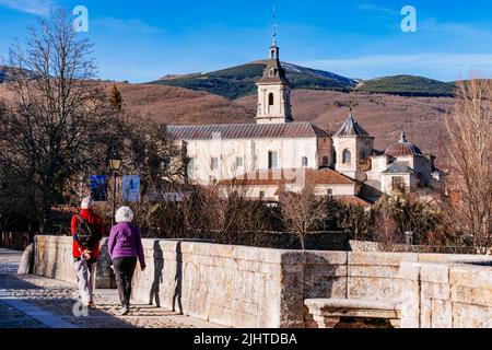 Die Puente del Perdón - Brücke der Begnadigung, ist eine steinerne Brücke über den Fluss Lozoya. Im Hintergrund das Monasterio de Santa María de El Paular - Stockfoto