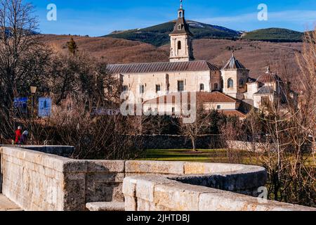 Die Puente del Perdón - Brücke der Begnadigung, ist eine steinerne Brücke über den Fluss Lozoya. Im Hintergrund das Monasterio de Santa María de El Paular - Stockfoto