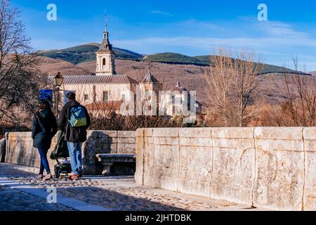 Die Puente del Perdón - Brücke der Begnadigung, ist eine steinerne Brücke über den Fluss Lozoya. Im Hintergrund das Monasterio de Santa María de El Paular - Stockfoto