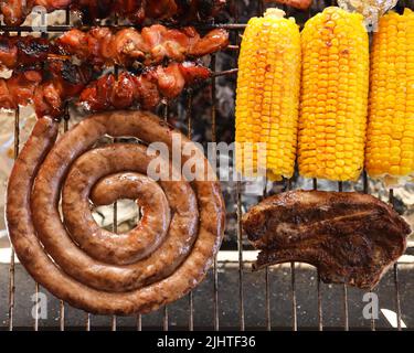 Traditionelle südafrikanische Braai. Braai oder Grill, bbq. Fleisch, das auf offener Flamme auf einem Braai-Gitter gekocht wird. Gegrilltes Fleisch und Gemüse Stockfoto