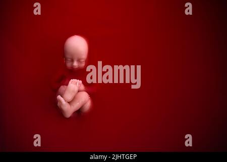 Abtreibungskonzept. Babypuppe im roten Blut sieht aus wie eine Abtreibung. Stockfoto