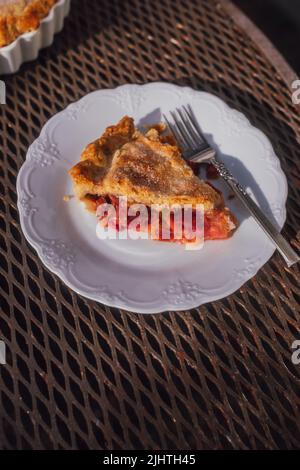 Eine Scheibe, eine Portion Rhabarber Pudding Pie auf weißem Teller, Außentisch Stockfoto