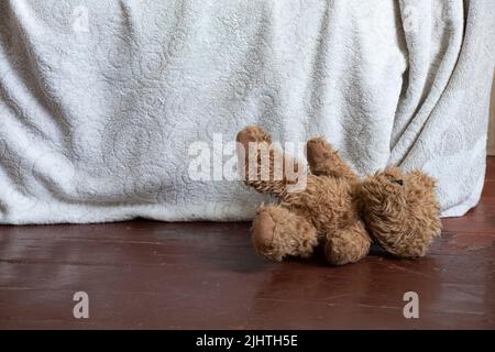 Ein Teddybär, ein Teddybär, liegt in der Nähe des Bettes auf dem Boden im Schlafzimmer zu Hause Stockfoto