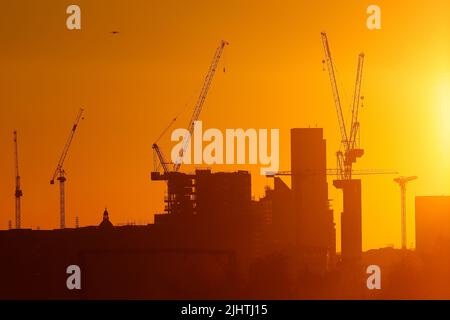 Turmdrehkrane im Zentrum von Leeds, West Yorkshire, Großbritannien, wurden gegen einen Sonnenaufgang silhouettiert Stockfoto