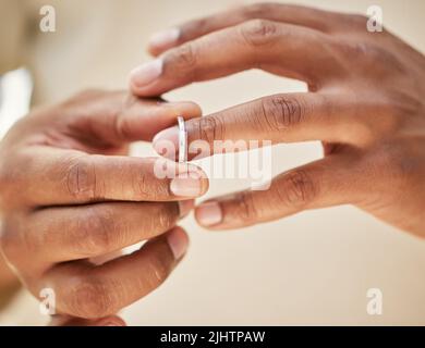 Mann, der das Hochzeitsband entfernt. Männliche Hände, die sich ausziehen, klingeln, bevor sie zum Betrügen ausgehen. Scheidung abschließen Stockfoto