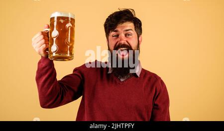 Oktoberfest. Fröhlicher Mann mit einem Glas Craft-Bier im Pub. Bärtiger Hipster mit Becher Ale. Stockfoto