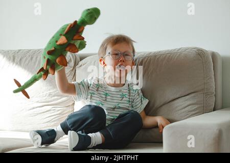 Ein Kind mit Autismus in einer Brille sitzt auf dem Sofa und traurig, wütend Stockfoto