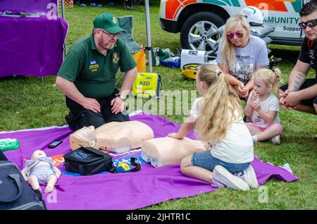 Ein Sanitäter, der einem Mädchen auf der „The Bukshire Motor Show“ in Reading, Großbritannien, die HLW an einer Schaufensterpuppe beibringt Stockfoto