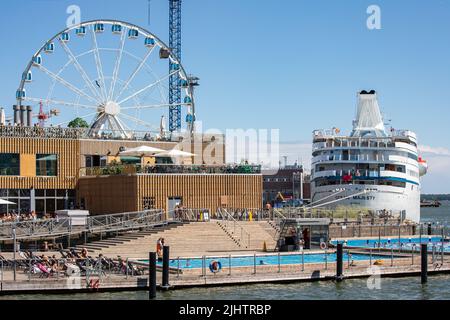 Schwimmende Poolterrasse des Allas Sea Pools mit Skywheel Helsinki und M/S Ocean Majesty im Hintergrund in Helsinki, Finnland Stockfoto