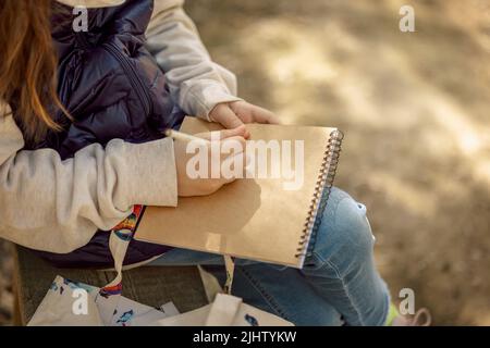 Kleines Mädchen malt im Frühling im Freien blühenden Märchenpark. Kinderzeichnungen. Kreatives Kind. Freude an der Kindheit. Hochwertige Fotos Stockfoto