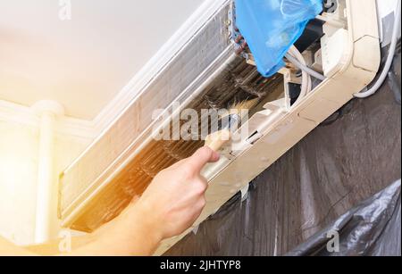 Ein Mann wäscht einen speziellen Schaum ab, um Klimaanlagen mit einem Wasserstrahl unter Druck zu reinigen. Wartung des geteilten Systems. Stockfoto